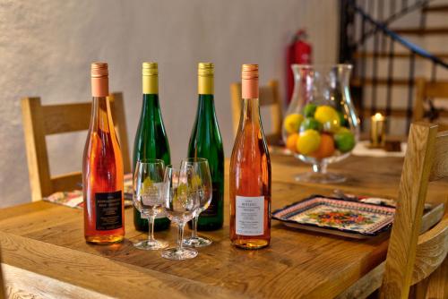 trois bouteilles de vin sur une table en bois avec des verres à vin dans l'établissement Weingut und Pension Markus Kochems, à Mesenich
