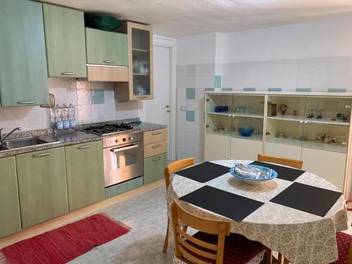 a kitchen with a table and a kitchen with green cabinets at Viniola Apartment in Quartu SantʼElena