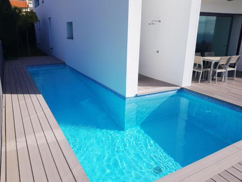 a blue swimming pool next to a building at Sunshine Villa 150m above Ocean & Sandy Beach in Estreito da Calheta