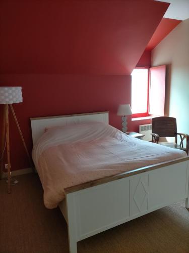 a bedroom with a white bed with a red wall at Le gîte des Serres in Parné-sur-Roc