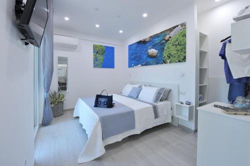 ein weißes Schlafzimmer mit einem Bett und einem TV in der Unterkunft La Casa Degli Amici in Sorrent