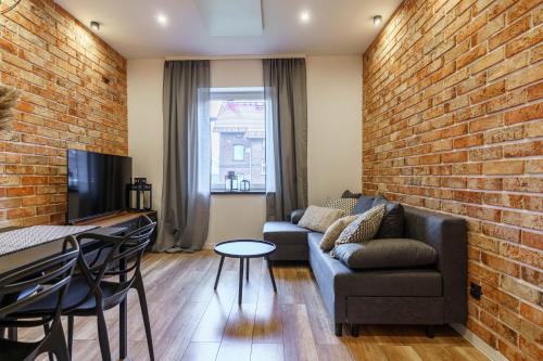 a living room with a couch and a brick wall at Loftowy apartament w sercu Śląska in Ruda Śląska