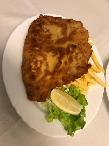 a white plate with a piece of meat and french fries at Hotel San Giobbe in Giubiasco