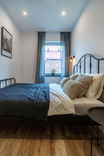 a bedroom with a bed with a blue blanket and a window at Loftowy apartament w sercu Śląska in Ruda Śląska