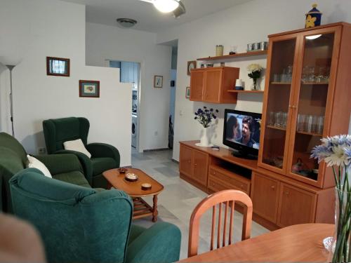 a living room with two green chairs and a television at Apartamento vacacional máximo 4 personas in Novo Sancti Petri