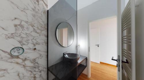 La salle de bains est pourvue d'un lavabo et d'un miroir mural. dans l'établissement Cozy apt w/ king bed great for discovering Liege, à Liège
