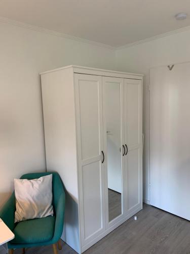 a room with a white cabinet and a green chair at Labud 25 am Plöner See in Bosau in Bosau
