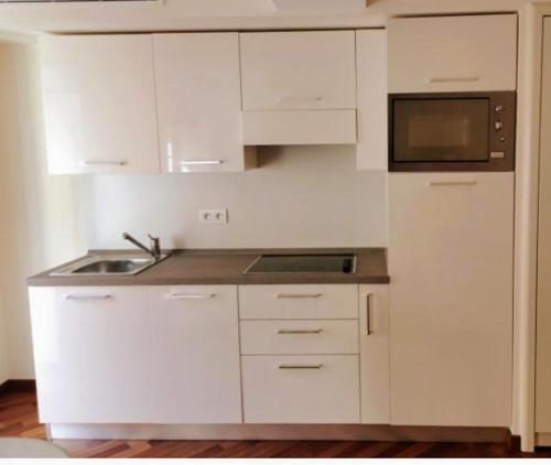 une cuisine blanche avec un évier et un micro-ondes dans l'établissement la perle de Menton, à Menton