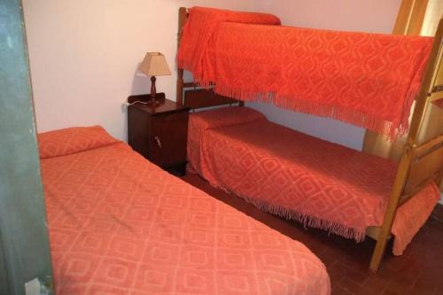 a bedroom with two bunk beds with red sheets at DEPARTAMENTO KRISTINA in Villa Carlos Paz