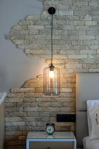 a light hanging from a brick wall with a clock at Paxos Luxury Living Junior Suites in Gaios