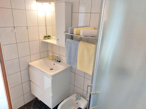 a bathroom with a sink and a toilet and towels at Vila Kraljica in Malinska