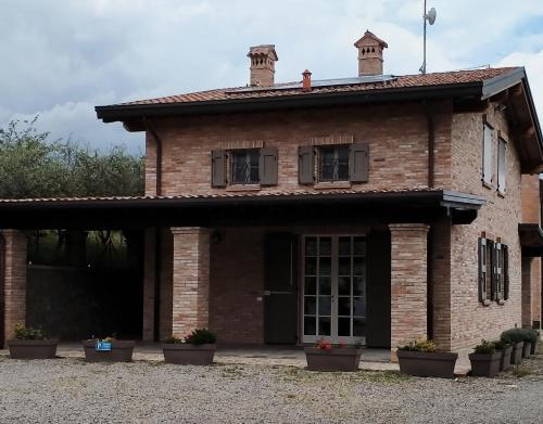 una vieja casa de ladrillo con macetas delante de ella en Affittacamere Maranello Locanda MoCa, en Il Poggio