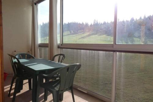 une table et des chaises dans une pièce avec une grande fenêtre dans l'établissement Appartement au pied des pistes 49m2 -4-5 pers, à Prémanon