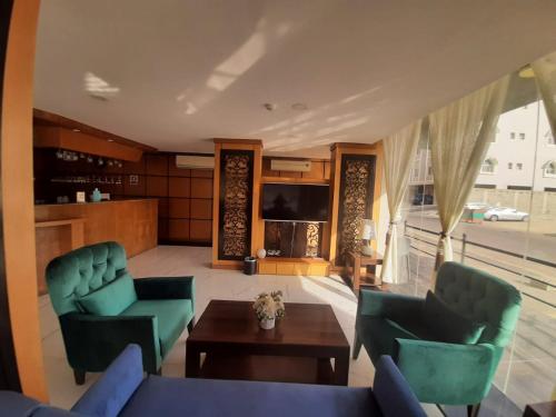 阿可賀巴的住宿－فندق سمأ الرفاع 2，客厅配有两张绿色椅子和一张桌子