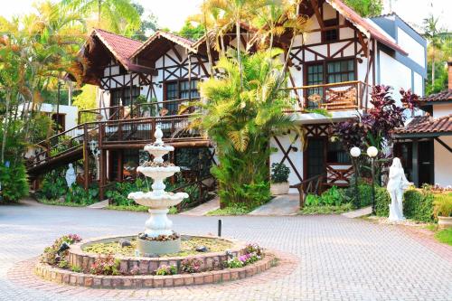 a fountain in front of a house with a building at Hotel Britannia in Penedo