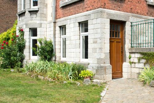 um edifício de tijolos com uma porta castanha e um quintal em Gîte Villa Léanne em Namur