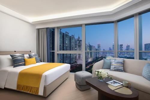 a bedroom with a bed and a couch and a large window at Star Residence ICC Guangzhou in Guangzhou
