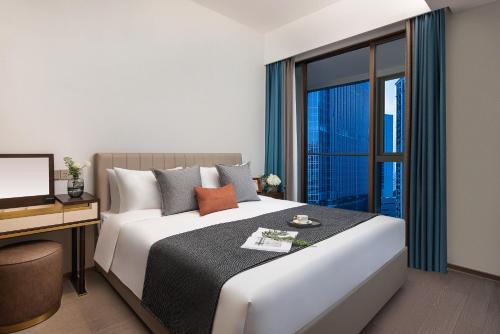 a bedroom with a bed with a desk and a window at Star Residence ICC Guangzhou in Guangzhou