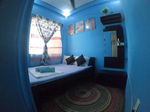 Habitación azul con cama y ventana en Casa Isabel Hostel, en Bantayan Island