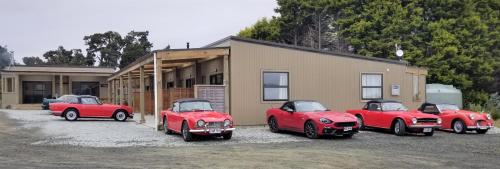 a group of red cars parked in front of a building at The Whistling Frog Resort in Chaslands