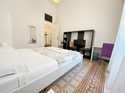 a white bedroom with a bed and a tv at Liolà Palermo in Palermo