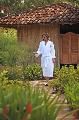 a woman in a white robe walking through a garden at InterContinental Costa Rica at Multiplaza Mall by IHG in San José