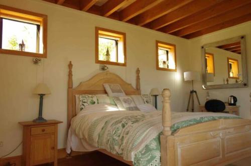 a bedroom with a wooden bed and two windows at Stunning Scandi Style Room Overlooking Lake Wanaka in Wanaka