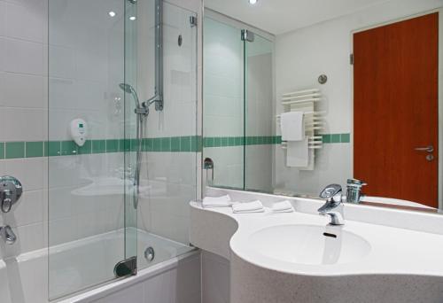 La salle de bains est pourvue d'un lavabo et d'une douche. dans l'établissement Wyndham Stralsund HanseDom, à Stralsund