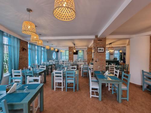 a dining room with blue tables and white chairs at Hotel Sunrise in Crisan