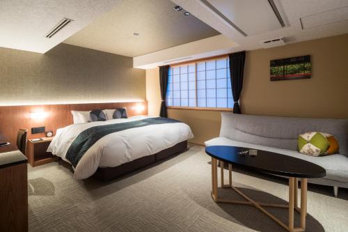 a hotel room with a bed and a couch at Homm Stay Nagi Arashiyama Kyoto By Banyan Group in Kyoto