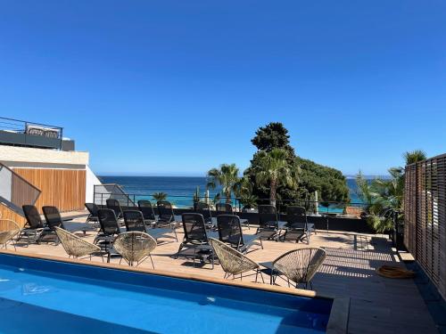 a pool with chairs and the ocean in the background at Les Alcyons in Le Lavandou