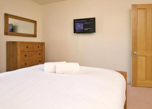 a bedroom with a white bed with a tv on the wall at Escape Ordinary at Castle Hume in Enniskillen