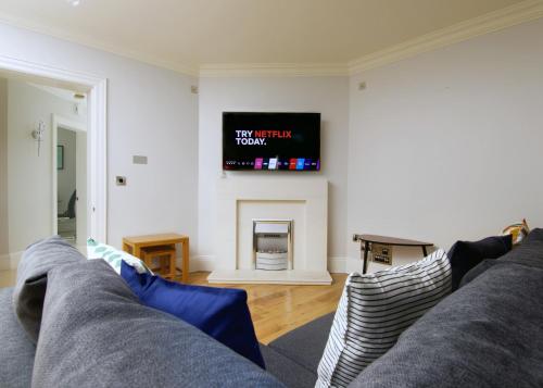 a living room with a couch and a tv on the wall at Escape Ordinary at Castle Hume in Enniskillen