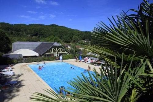 una gran piscina con gente sentada a su alrededor en Chalet les Hameaux du Perrier, en Lissac-sur-Couze
