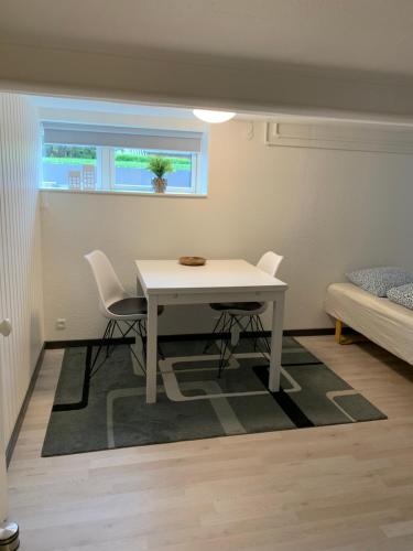 a white table and chairs in a room with a window at H. C. Lumbyes Vej - kælderlejlighed in Odense