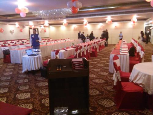 a banquet hall with white tables and red chairs at The Fern Residency Rajkot in Rajkot