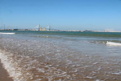 a beach with the ocean and a bridge in the background at Oceanum Visum Spa Deluxe in El Trocadero