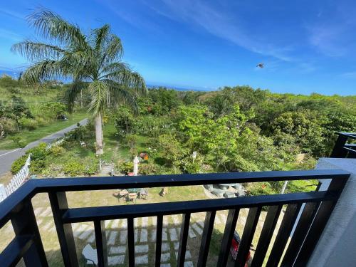 a balcony with a view of a palm tree at Lanshan House in Donghe