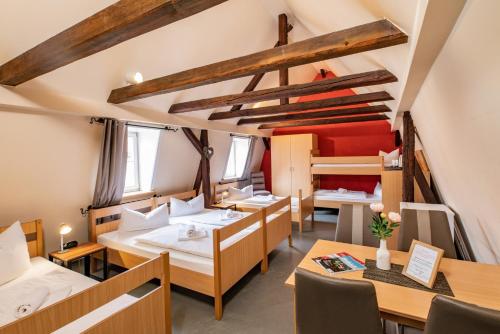 Zimmer mit Betten, Tischen und einem Etagenbett in der Unterkunft Gasthof-Gästehaus am Storchenturm in Eisenach