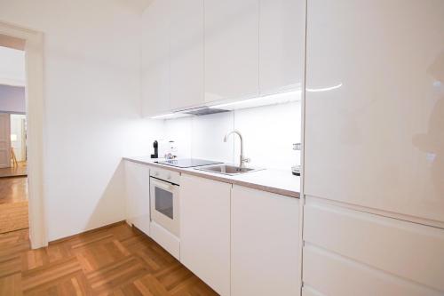 una cocina blanca con armarios blancos y fregadero en Apartment Congress Graz en Graz