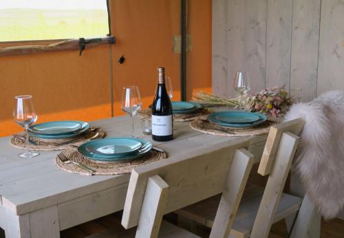 een tafel met borden en een fles wijn bij Luxe safaritenten Petit013 - nieuw in Tilburg
