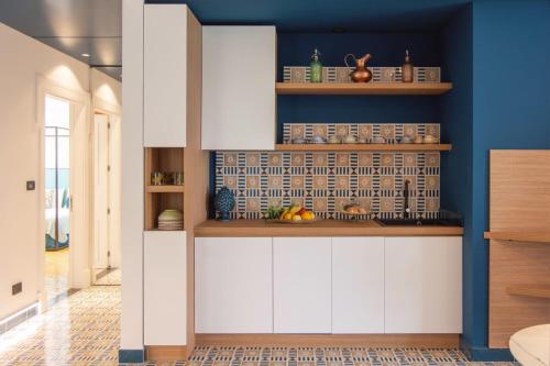 une cuisine avec des placards blancs et un mur bleu dans l'établissement B&B Nicotera29, à Vico Equense
