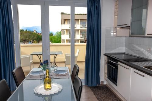 シルミオーネにあるMonica Appartamentiのガラステーブルと椅子、バルコニー付きのキッチンが備わります。