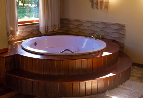 una gran bañera de madera en un baño con ventana en Pousada Chalé Amoreira, en Visconde De Maua