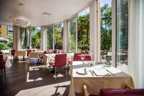 a restaurant with tables and chairs and large windows at Tertianum Residenza Al Lido - Appartements & Restaurant in Locarno