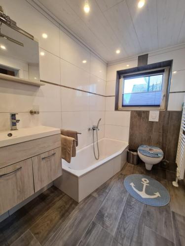 a bathroom with a tub and a toilet and a sink at Haus Seestern in Dornumersiel