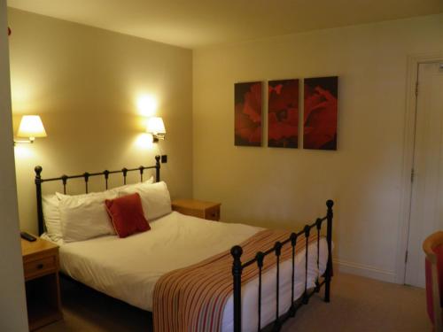 1 dormitorio con 1 cama con sábanas blancas y almohadas rojas en The Talbot Inn en Oxford