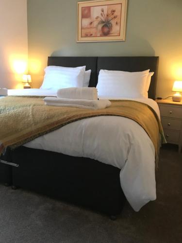 a bedroom with a large bed with white sheets and pillows at The Lodge in Llangollen