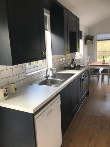 a kitchen with black cabinets and a white counter top at The Lodge in Llangollen