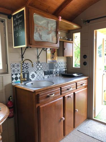 - une cuisine avec un évier et un tableau noir sur le mur dans l'établissement Roulotte à Honfleur, à Honfleur